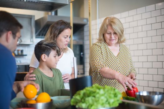 Three generations preparing a meal together in a modern kitchen, fostering family bonds and culinary skills.