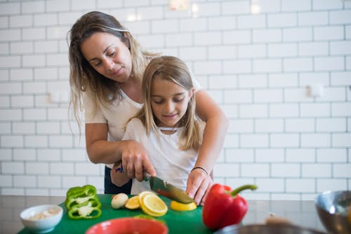 Girl in White Tank Top Assisting Daughter to Chop Lemon