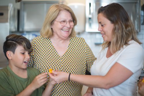 Free Three generations laughing and bonding in a bright, modern kitchen. Stock Photo