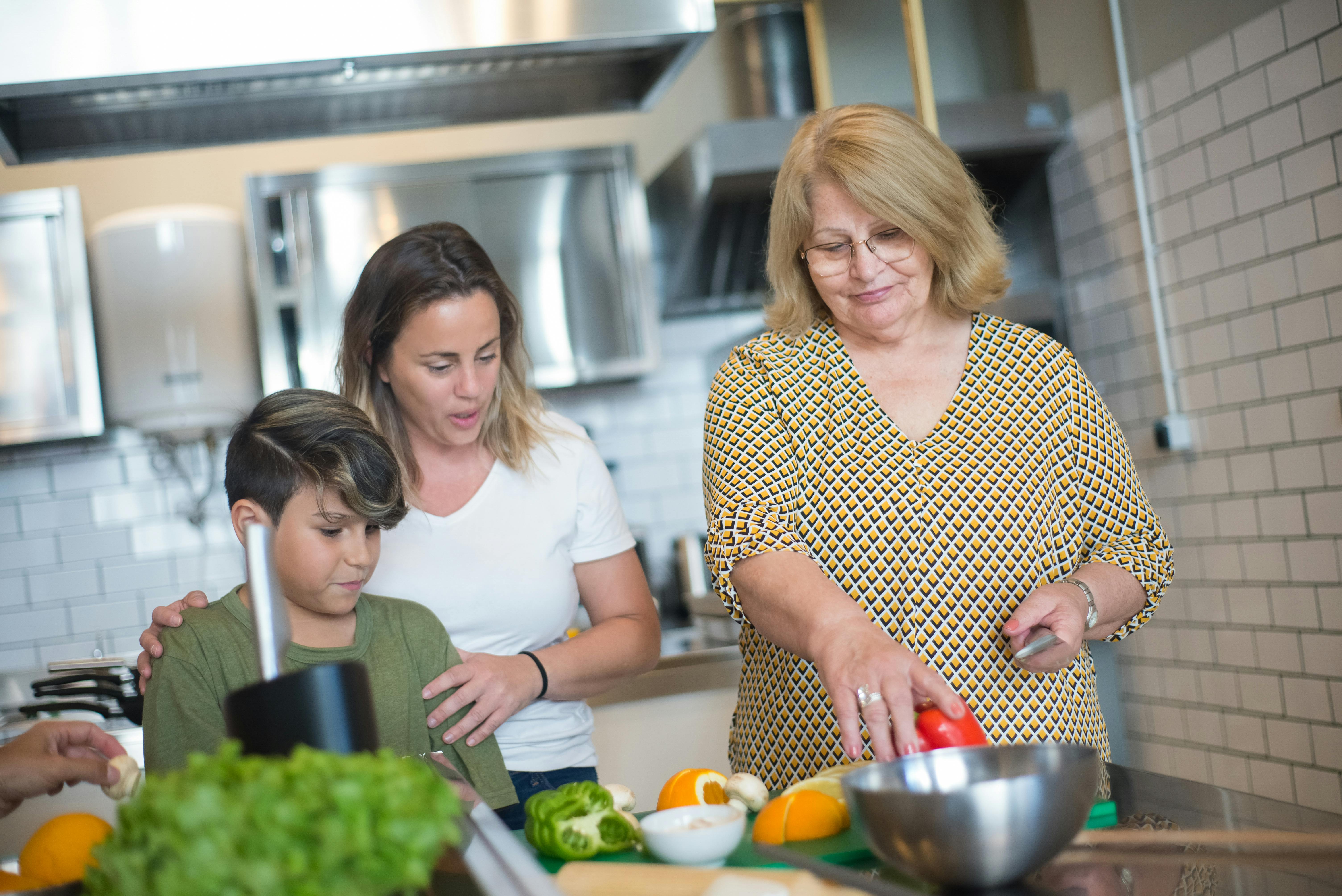 woman in yellow and black shirt holding a knife and red bell pepper