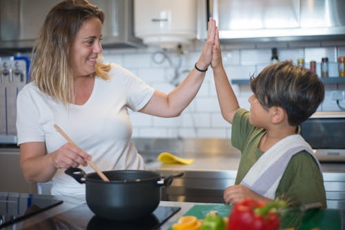 A Mother and Her Son Giving a High Five while Cooking