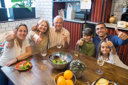 Family Sitting at Table and Showing Thumbs Up