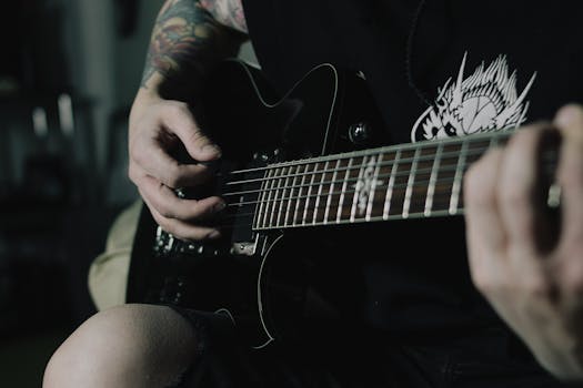 A tattooed musician strumming an electric guitar, creating moody vibes.