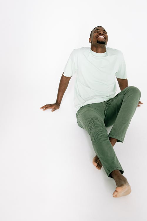 A Man in White Shirt Smiling while Sitting on a White Surface