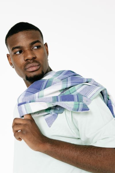 Man holding a checked overshirt across his shoulder — photo by Ivan S on Pexels