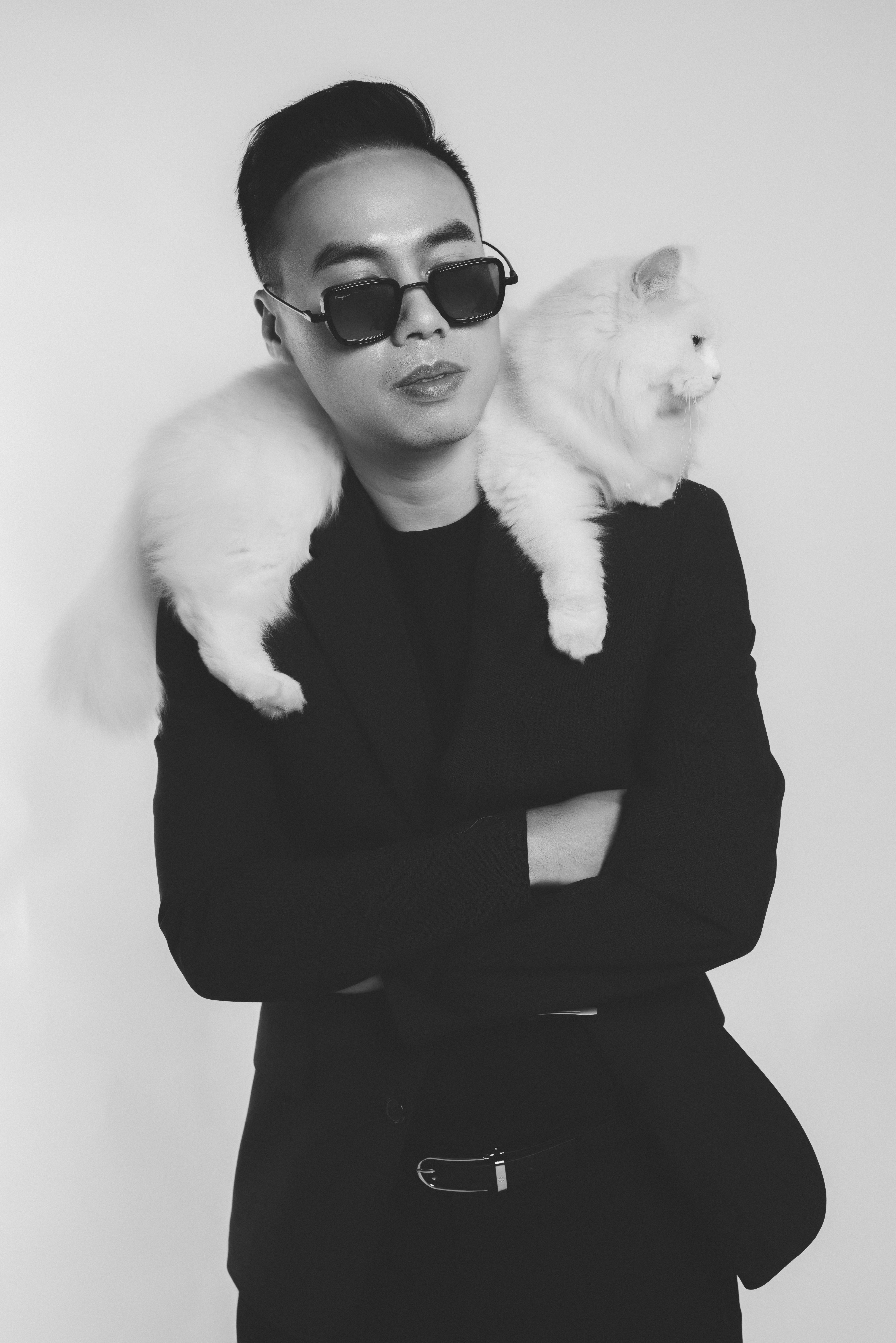 Chic black and white portrait of a man with a Persian cat on his shoulder.