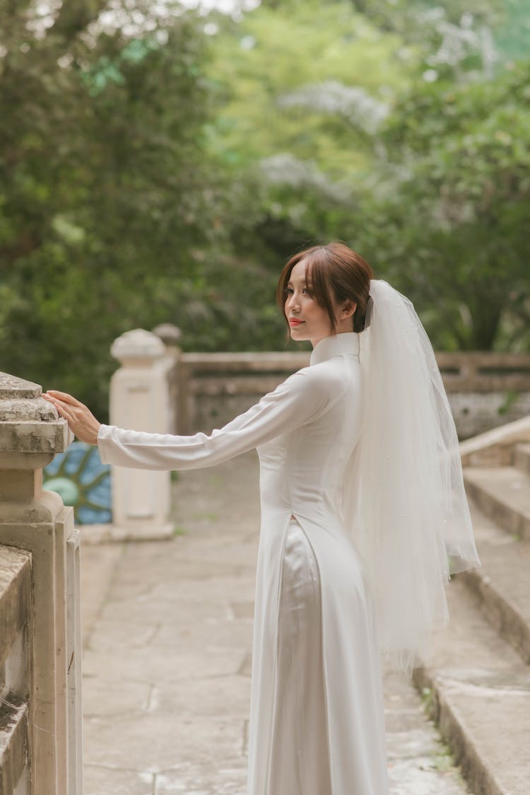 Woman In White Wedding Dress Holding On A Post