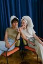 Women Sitting on the Chair Smiling while Doing Pinky Swear