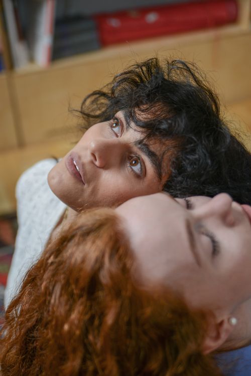 Free Intimate portrait of two young women with contrasting hair colors lying together indoors. Stock Photo