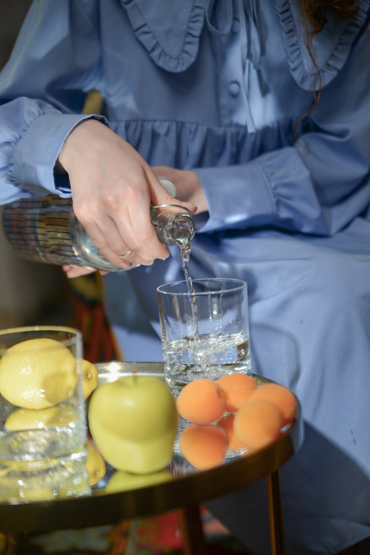 A Person Pouring Water In A Drinking Glass