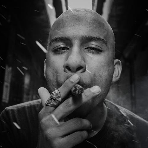 Grayscale Photo of a Bald Man Smoking Cigarette