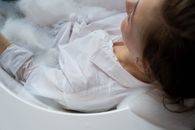 Woman in White Button Up Long Sleeves Resting on a Bathtub with Water