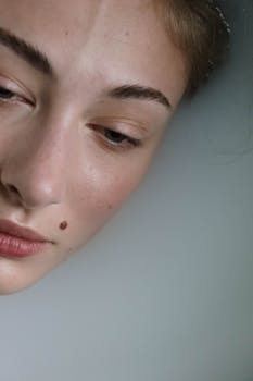 Artistic close-up portrait highlighting natural beauty with freckles and mole.
