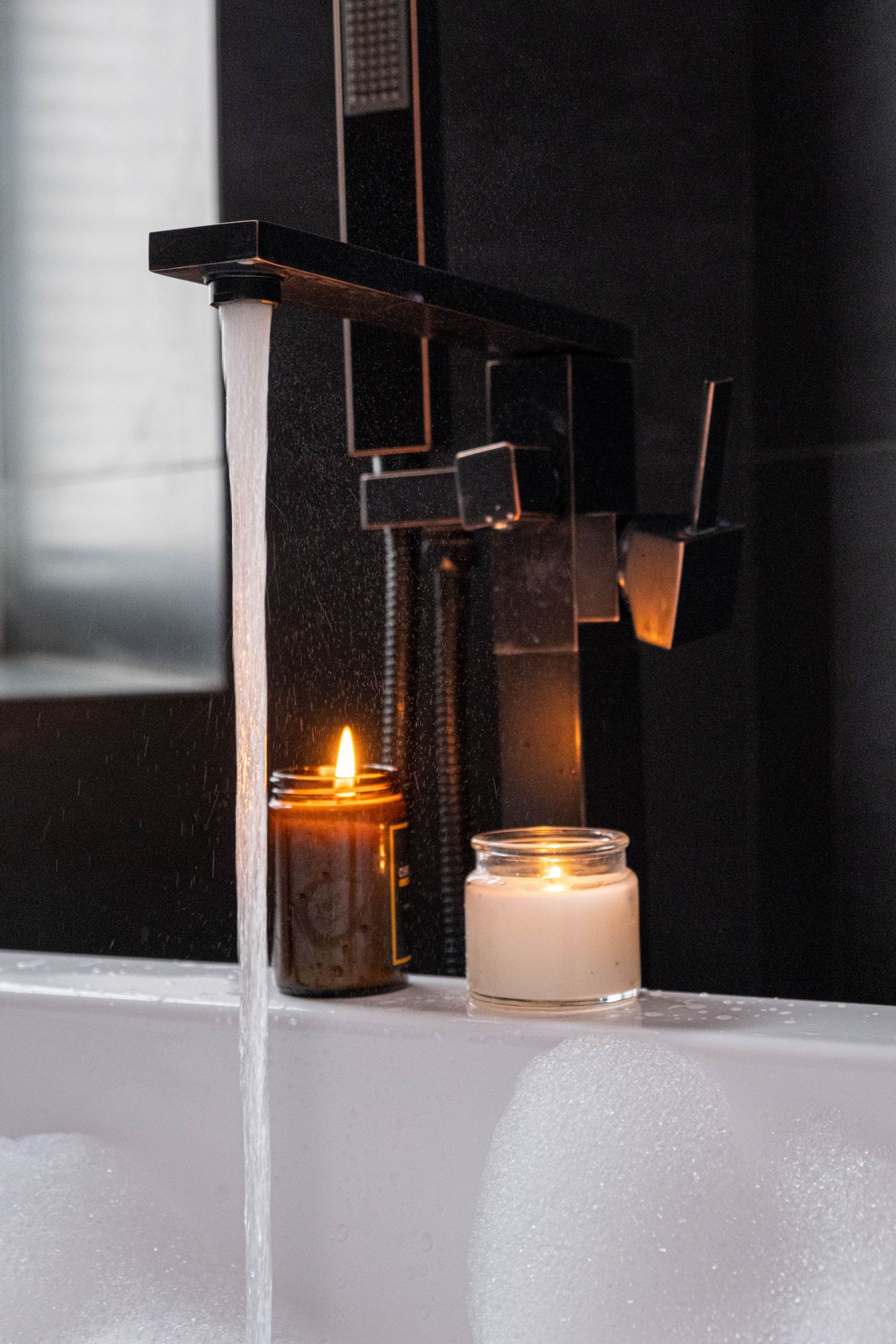 Velas encendidas junto a una bañera con estética de spa de hotel