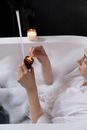 A Woman Resting on the Bathtub while Lightning the Candle on a Jar