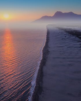 Breathtaking aerial view of a serene coastline at sunrise, capturing the warm glow over the ocean.