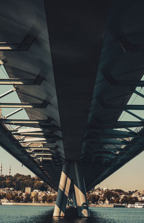 Free A contemporary bridge spans over a harbor with buildings in the background on a clear sunny day. Stock Photo