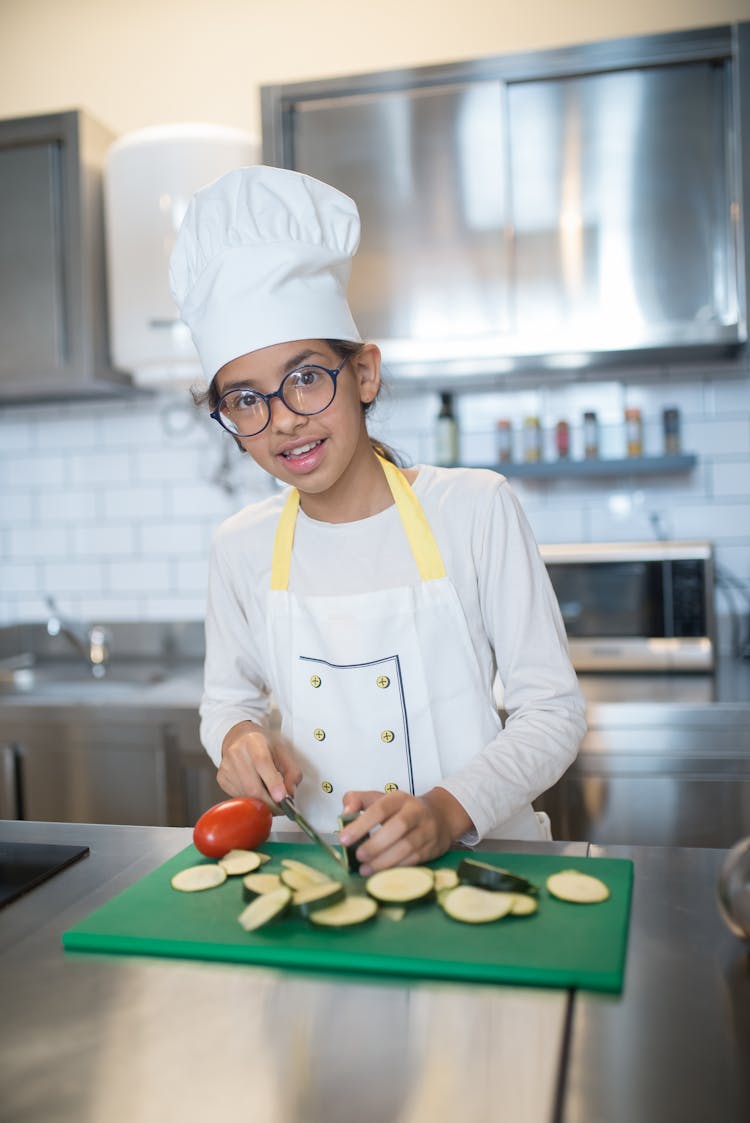 A Girl In White Long Sleeves Slicing Vegetables