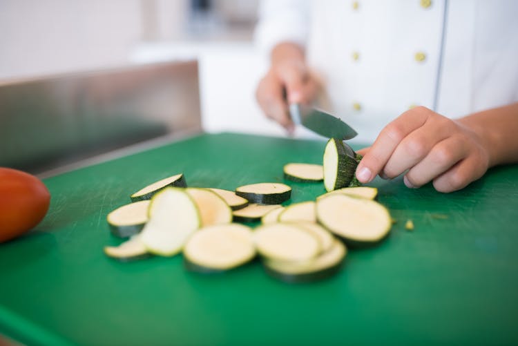 A Hands Slicing Cucumber On The Chopping Board