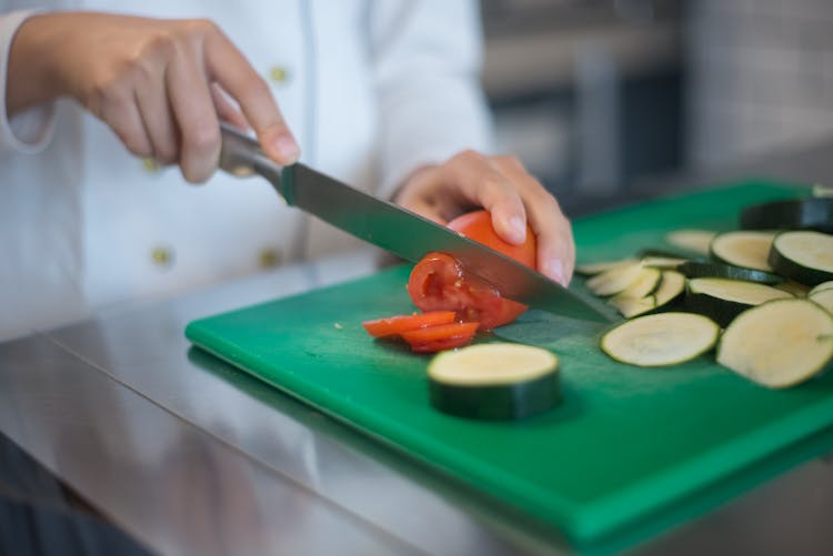 A Person Slicing A Tomato