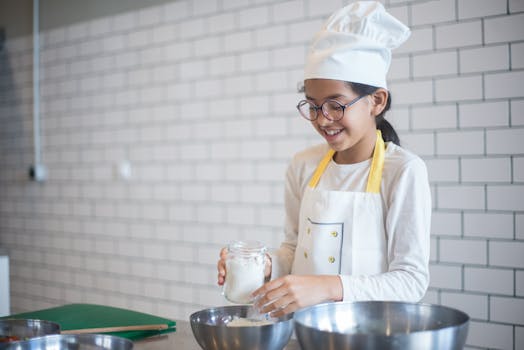 A young girl learning to cook, smiling and enjoying her culinary activity.