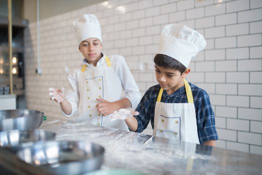 Young Kids Wearing Toque and Aprons Inside the Kitchen while Playing Flour