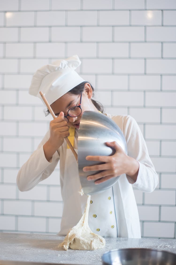 A Girl Putting The Dough On The Countertop From The Stainless Bowl