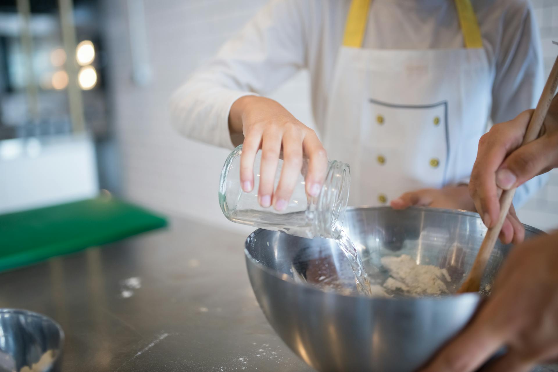 A Hand Pouring Water on the Stainless Bowl