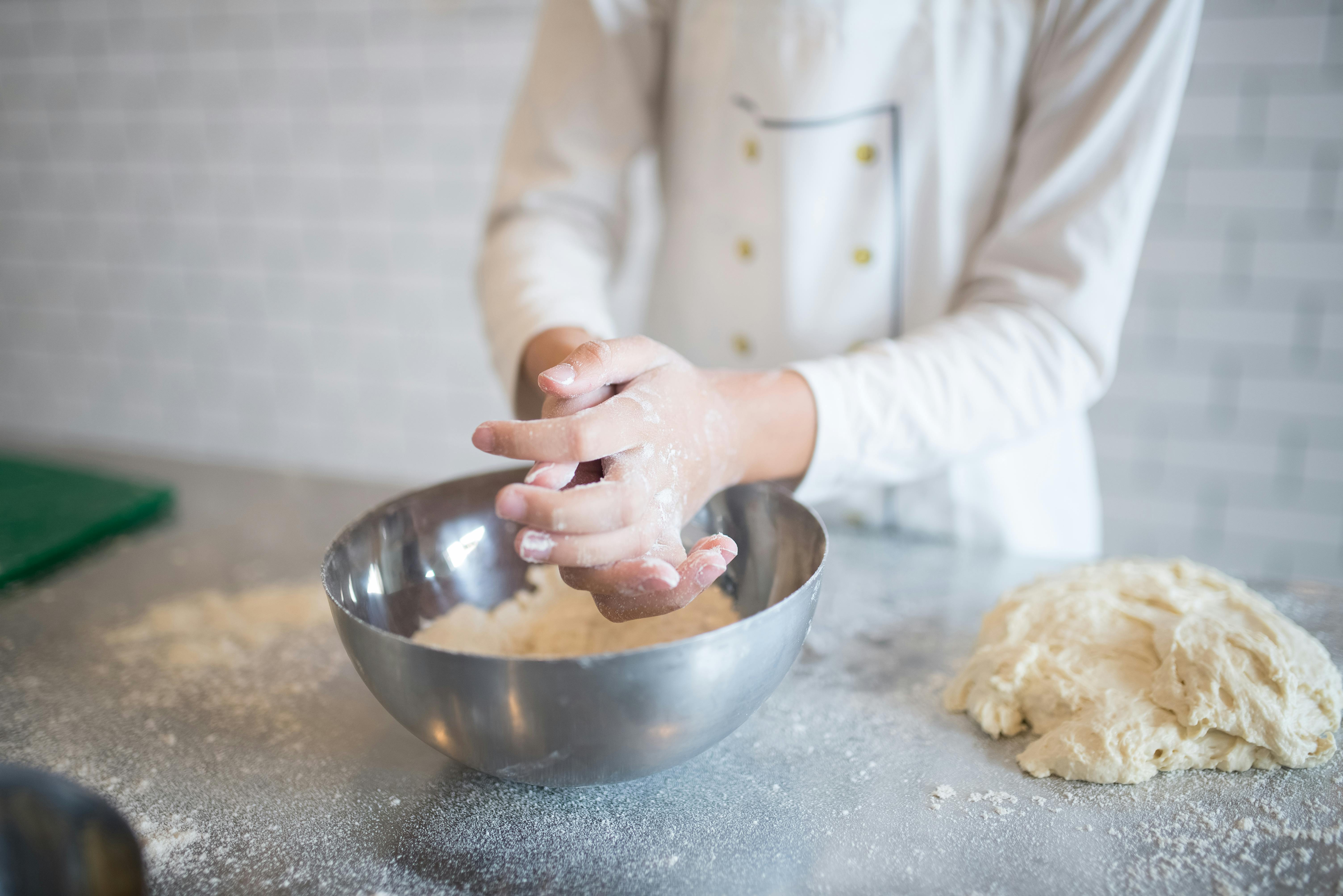 Pastry chef pouring flour with help of wooden spoon to blender