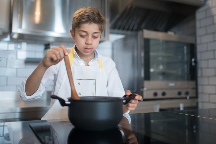 A Young Boy Stirring A Pot