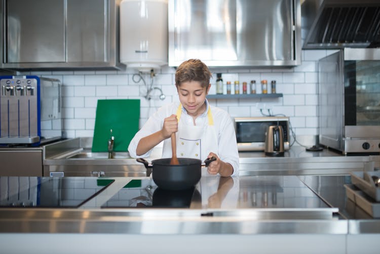 A Young Boy Stirring A Pot