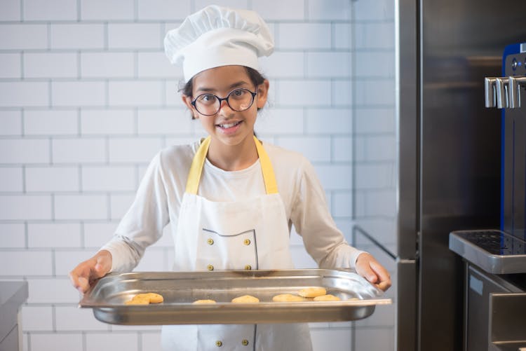 A Young Girl Carrying A Tray Of Cookies