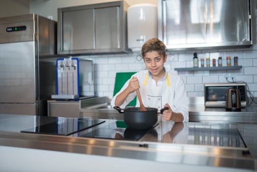 A young boy in a kitchen stirring a pot, showcasing culinary skills.
