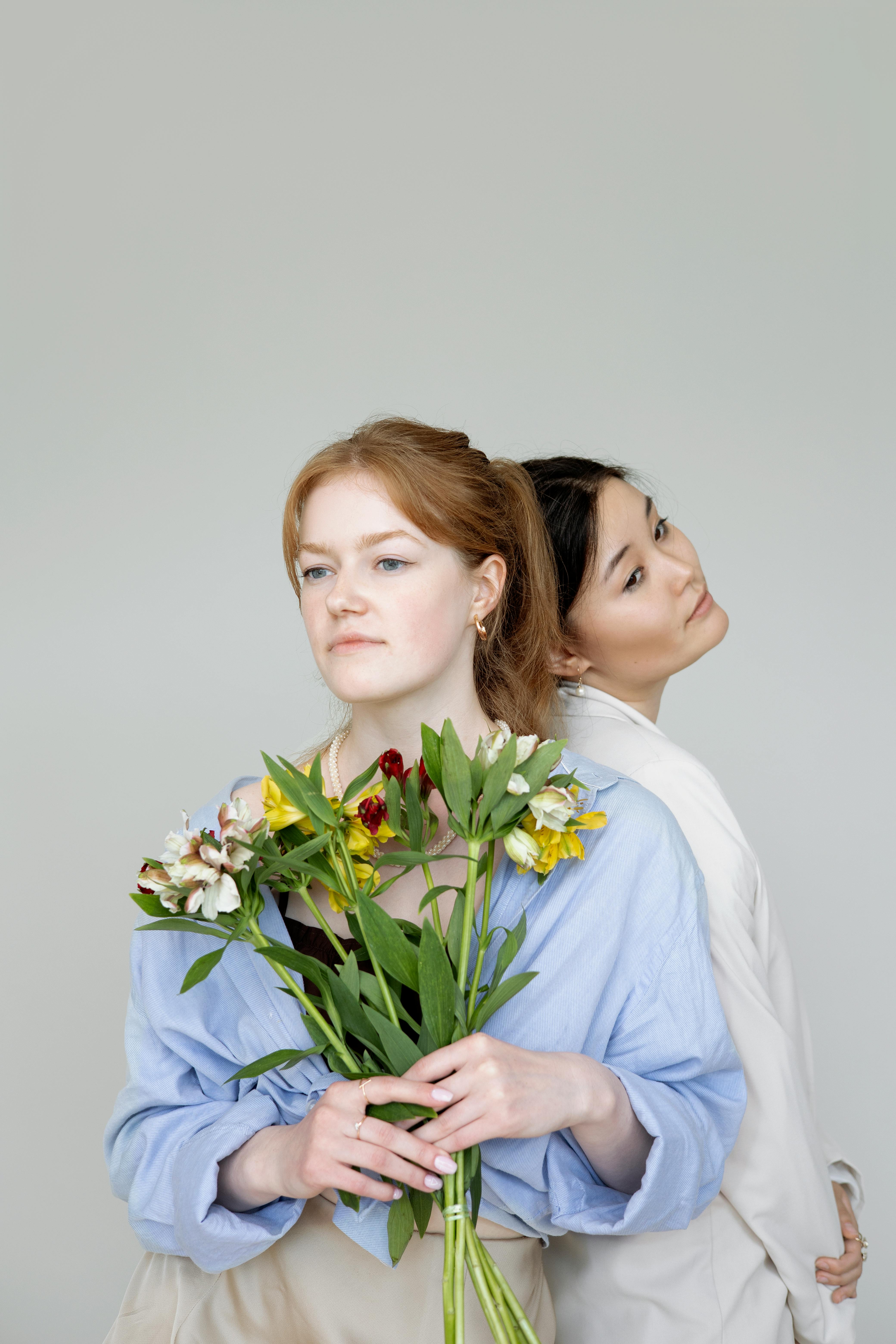 woman in blue long sleeve shirt holding white and yellow flowers