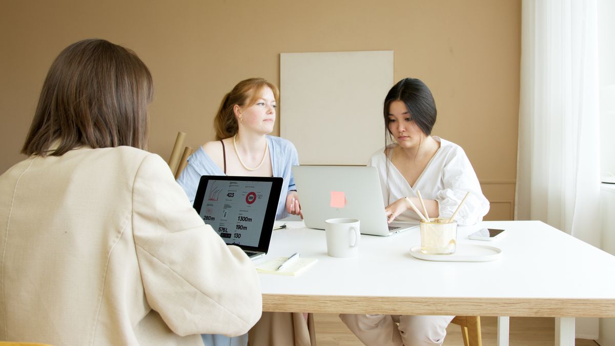 Three colleagues planning and brainstorming with laptops in a bright modern office