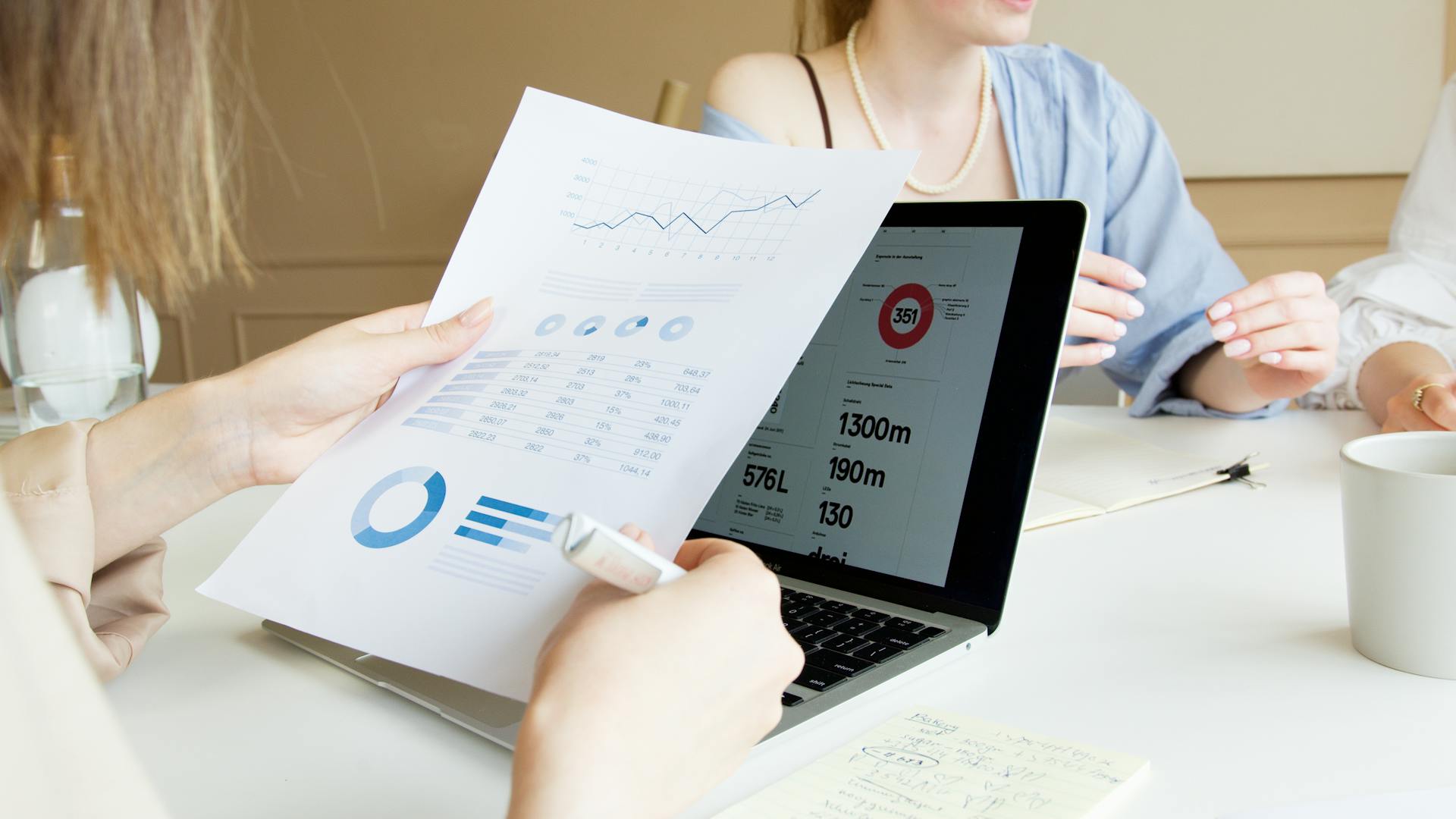 Close-up of professionals reviewing financial charts and data on laptop in a meeting.