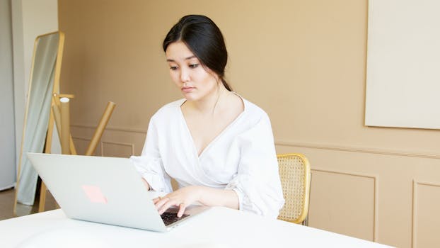 Asian businesswoman in a bright office working diligently on her laptop.