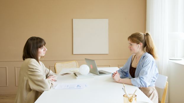 Woman in Blue Long Sleeve Shirt Sitting Beside Woman in White Long Sleeve Shirt
