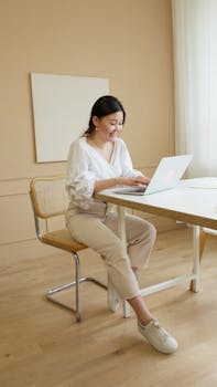 A woman professionally dressed, working on a laptop in a modern office, conveying productivity and modern work culture.