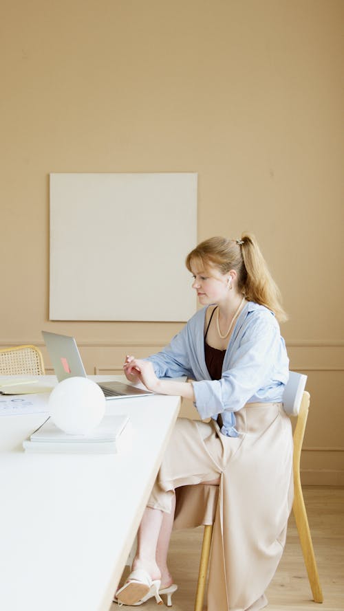 Free Woman Sitting on a Chair while Working on Her Laptop Stock Photo