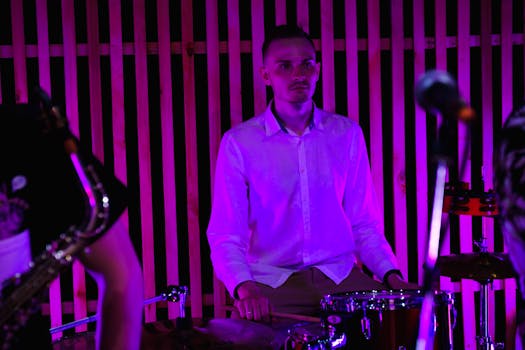 Drummer performing live at a concert with vibrant lighting.