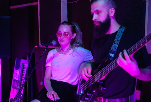 Man in Black Crew Neck T-shirt Holding Electric Bass Guitar Beside Woman
