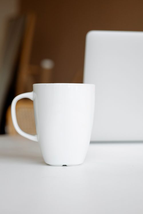 Free Simple white ceramic mug on desk near laptop, modern minimalism. Stock Photo