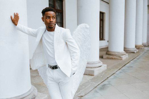 A Man Wearing an Angel Costume Leaning on a Pillar