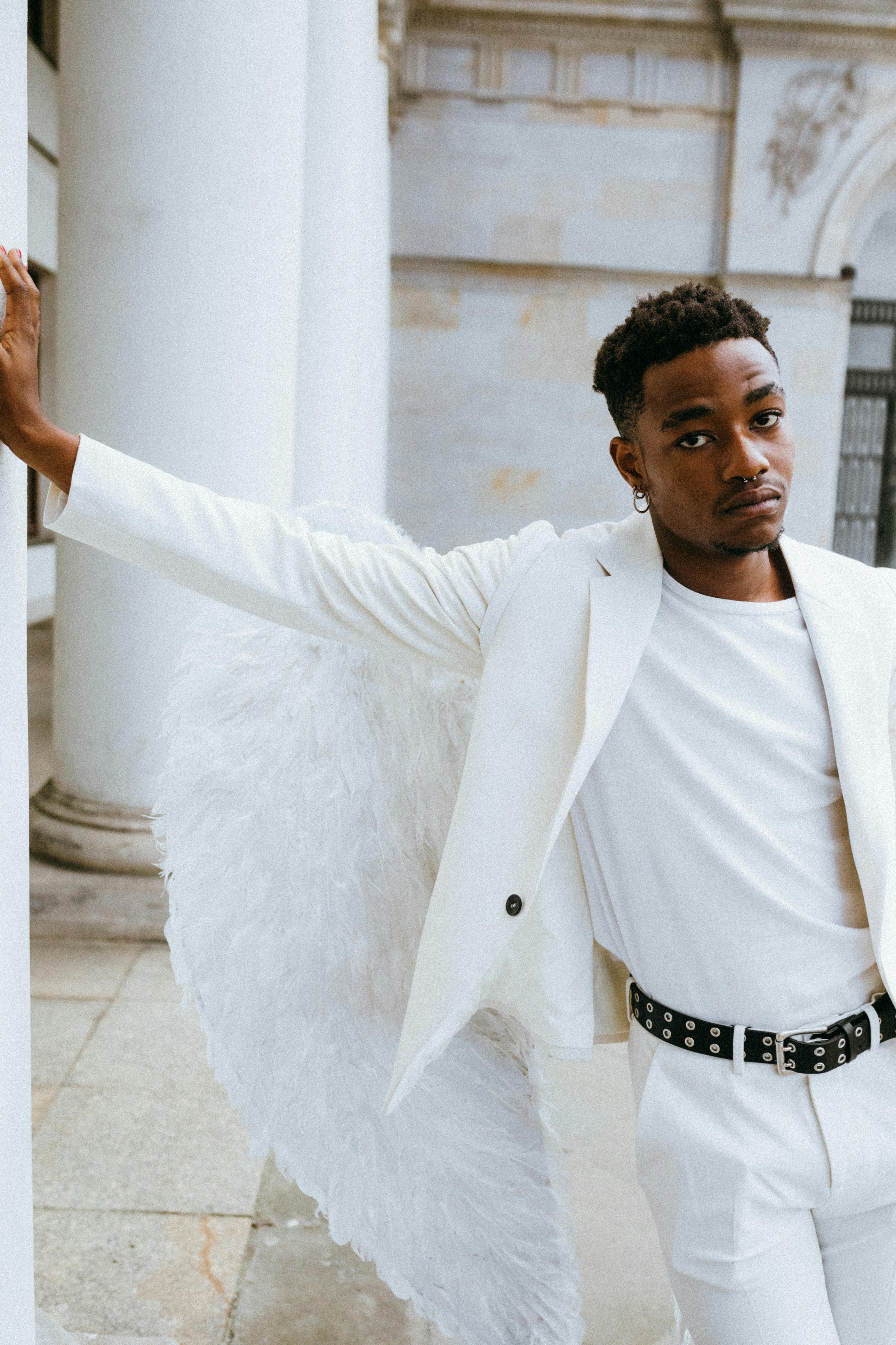 a man wearing an angel costume leaning on a pillar