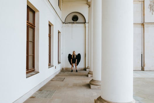 A striking image of a woman in black dress with angel wings amid grand columns, evoking a mystical aura.
