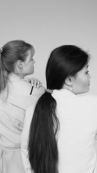 Artistic grayscale photo capturing the back view of two women, focusing on texture and contrast.