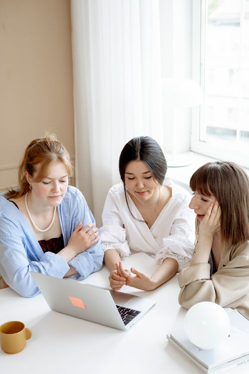 Free Three women in an office setting collaborating over a laptop, fostering teamwork and innovation. Stock Photo