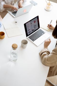 High angle view of businesswomen working with laptops and documents at a modern office desk.
