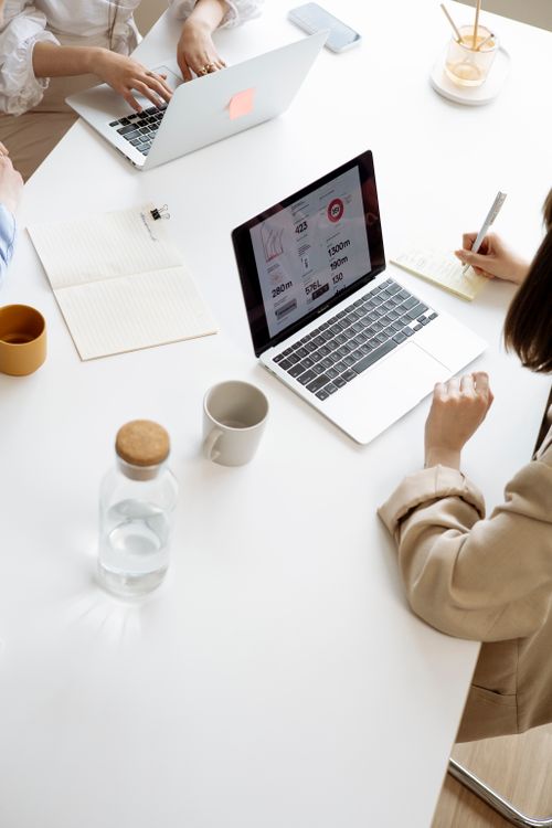 Free High angle view of businesswomen working with laptops and documents at a modern office desk. Stock Photo